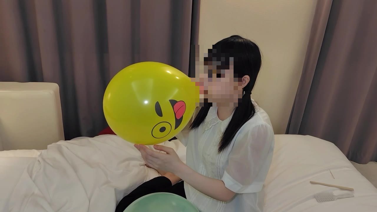 黄色い顔の絵の風船を大きくふくらませるひなた