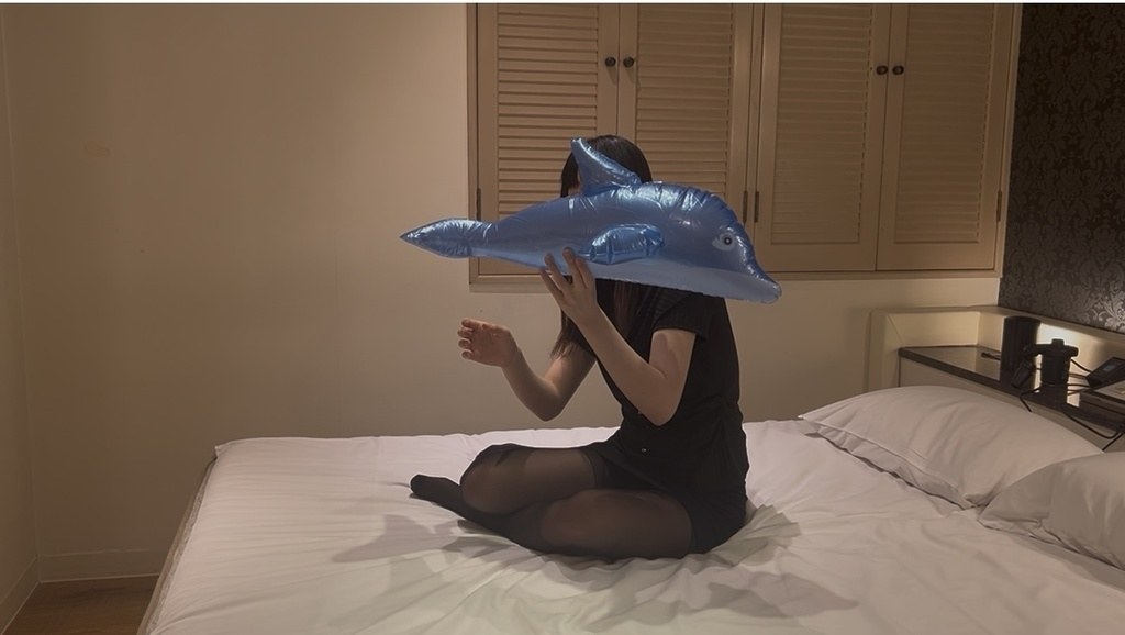 ふくらんだビニールのイルカを口元で持ち上げるひなた