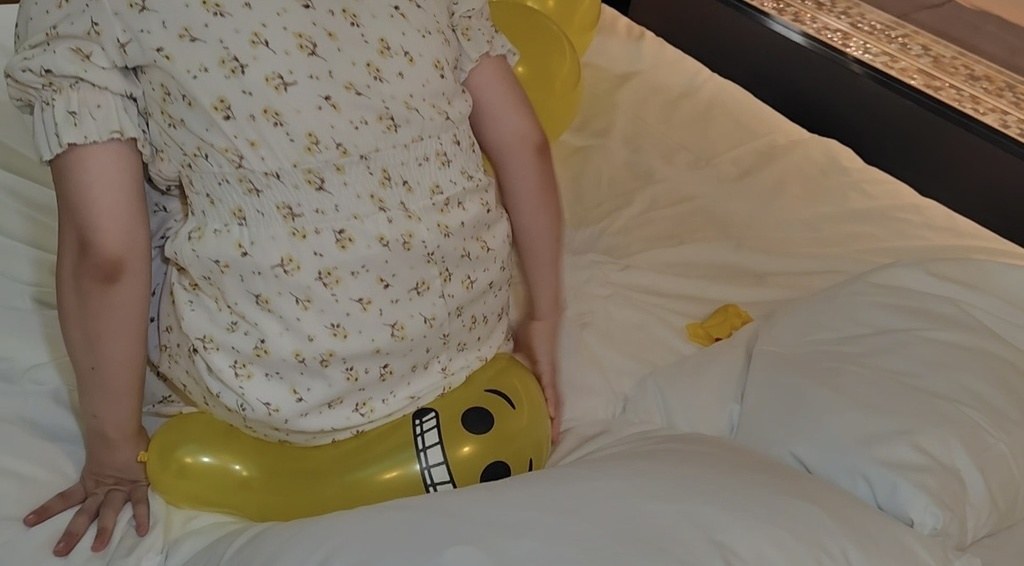 黄色い風船の上に座って体重をかけるゲストモデルAさん