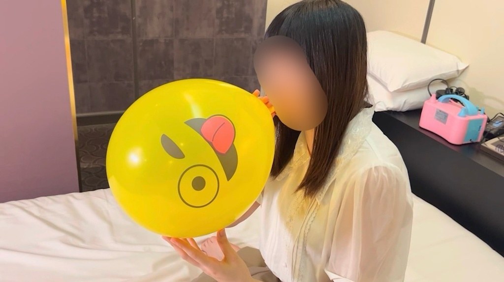 大きな黄色い顔風船を口でふくらませるひなた