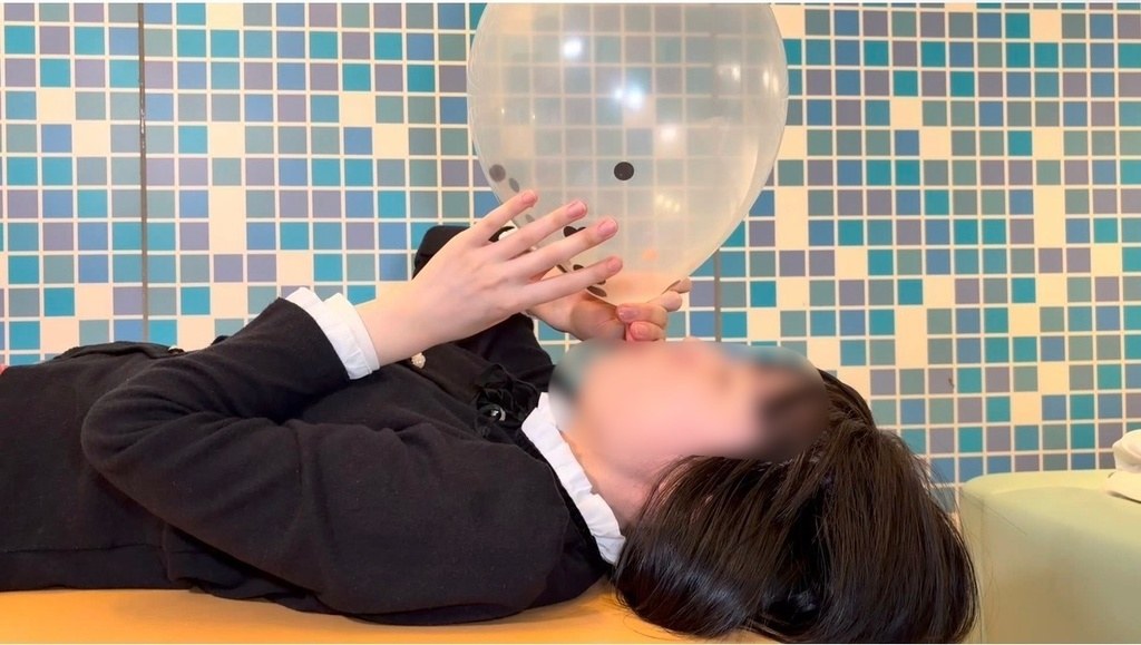 仰向けで透明な風船をふくらませるひなた