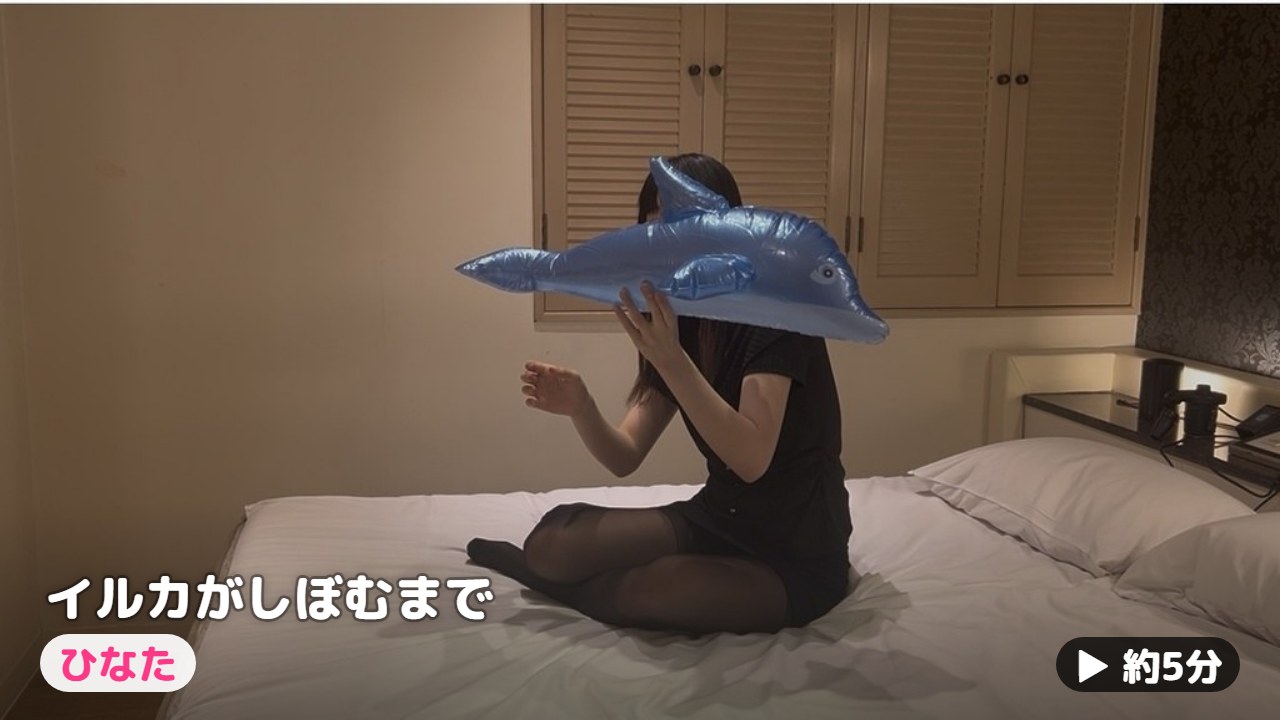 ふくらんだビニールのイルカを口元で持ち上げるひなた