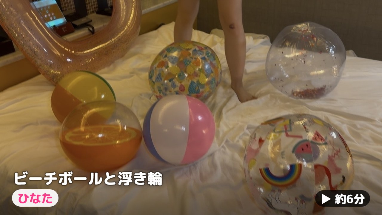 色とりどりのビーチボールの間に立つひなたの素足