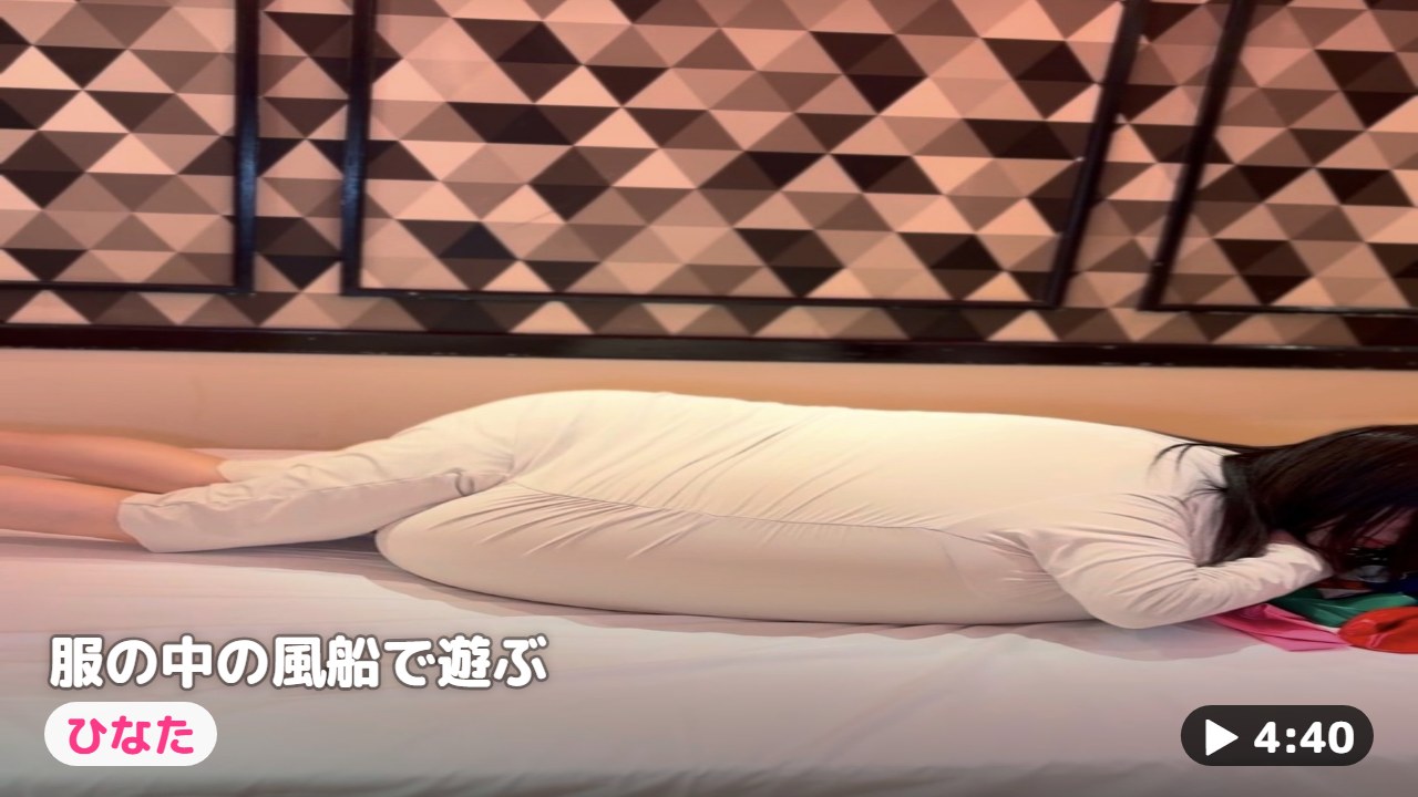服の中の風船を抱えてベッドに横になるひなた