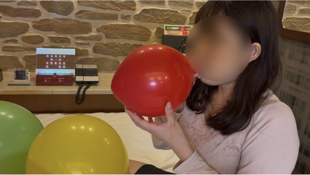 赤い16インチ風船を口でふくらませるゲストモデルBさん