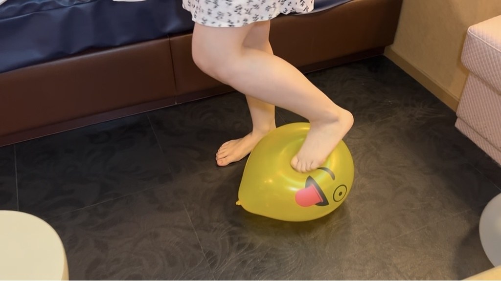 素足で黄色い顔付き風船を踏むひなた