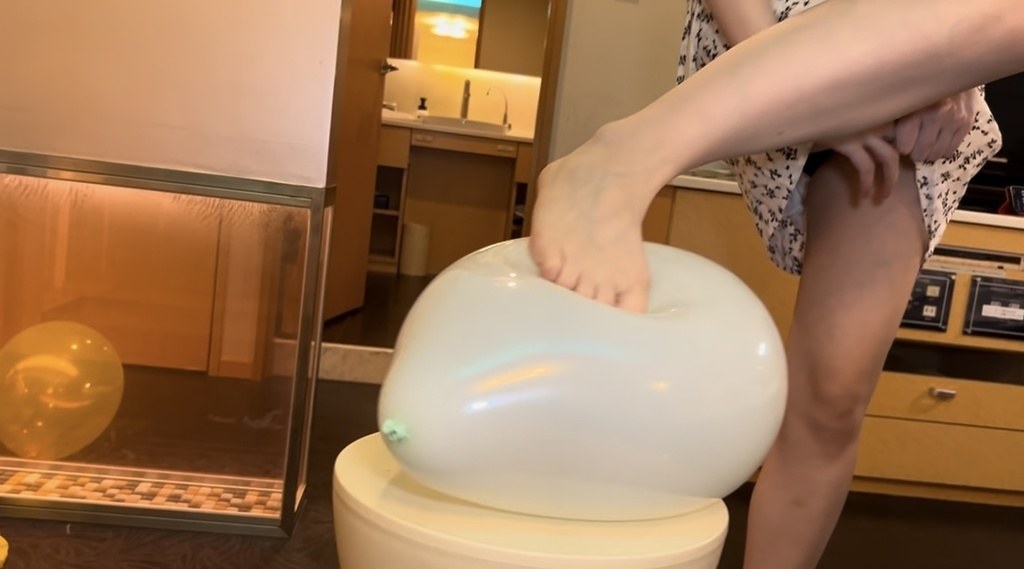 スツールにのせた白い風船を素足で踏むひなた
