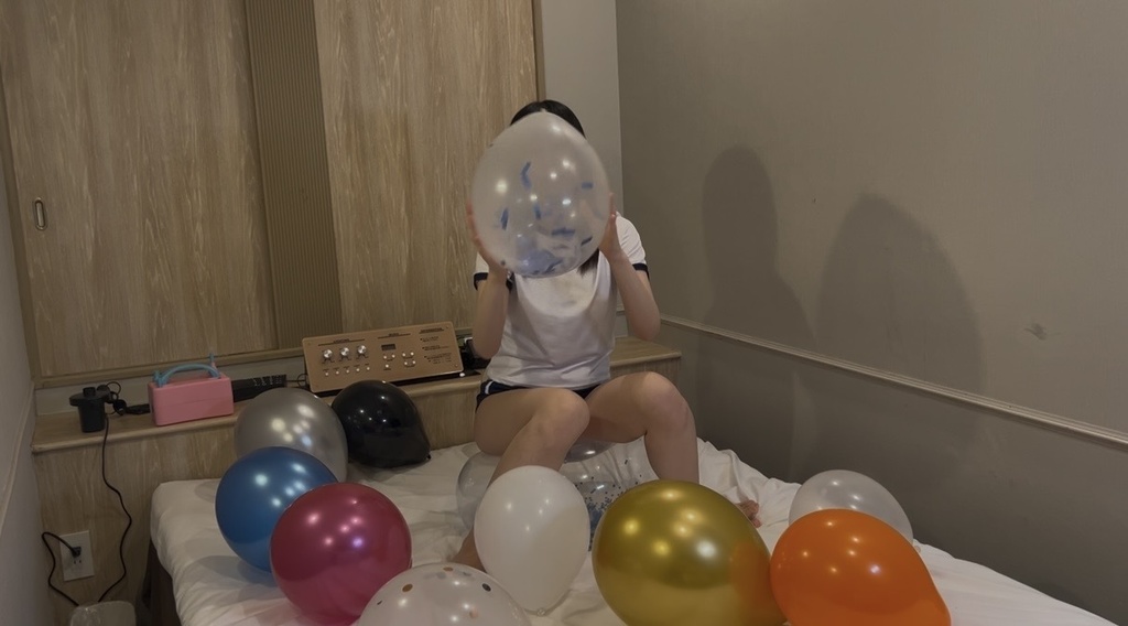 ふくらませた風船に囲まれてビーチボールに座るひなた