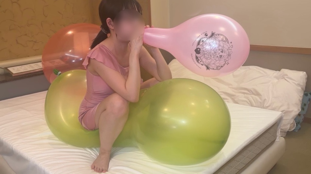 大きな緑の風船にまたがり、キャラクター風船をふくらませるひなた