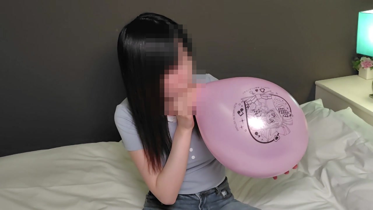 ピンクのキャラクター柄の風船を口でふくらませるひなた