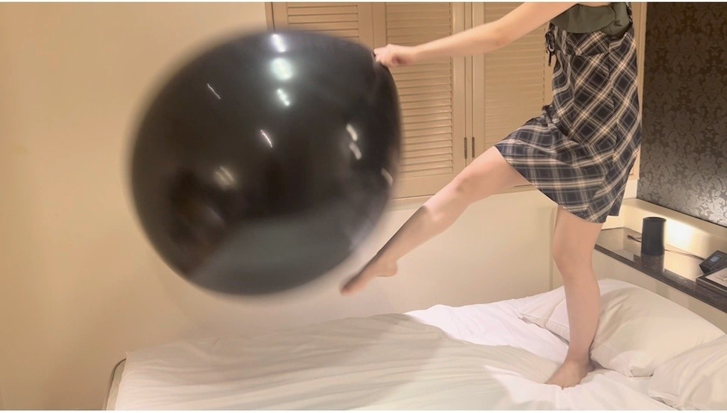 黒い巨大風船を脚で蹴り上げるひなた
