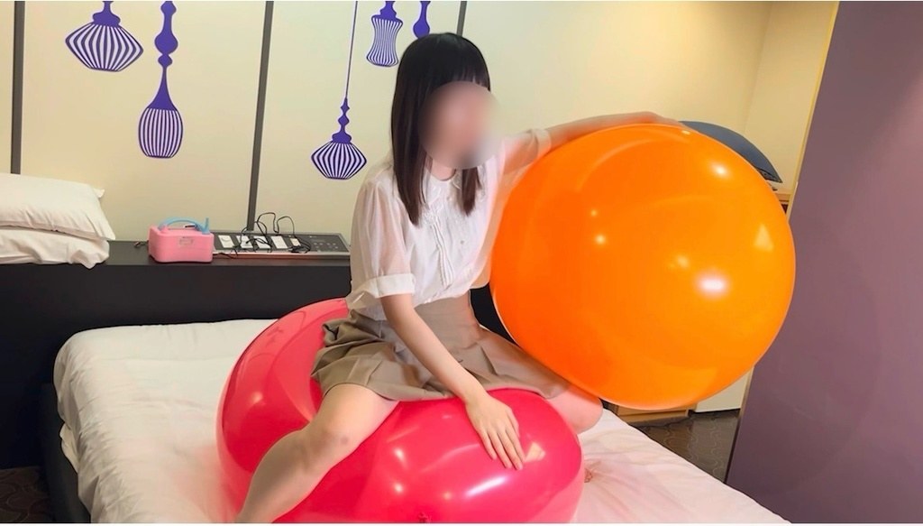 ピンクの巨大風船にまたがりオレンジの巨大風船に手をのせるひなた