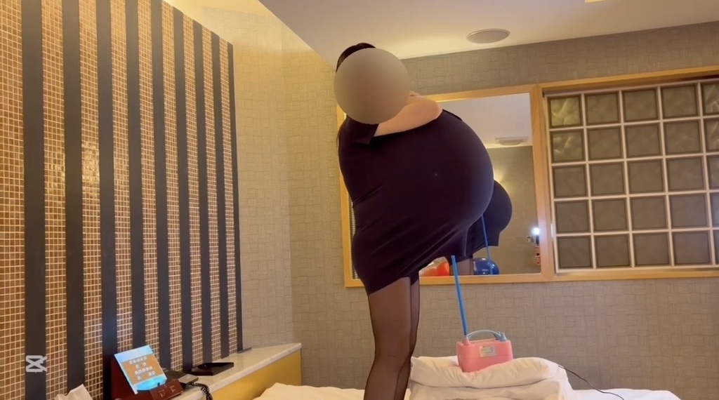 立ったまま、ワンピースの中で風船をふくらませるひなた