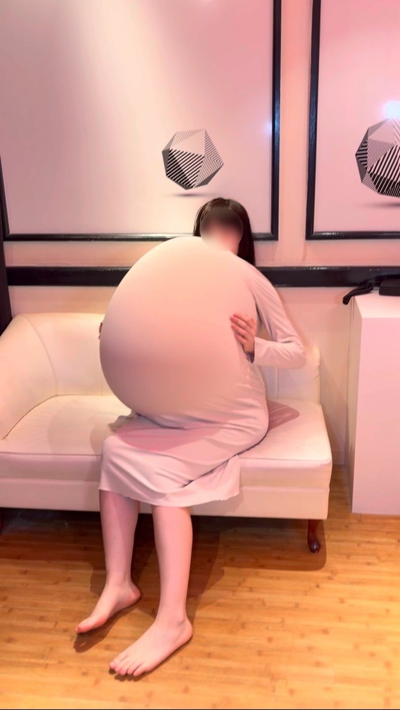 服の中の大きな風船を抱えてソファに座るひなた