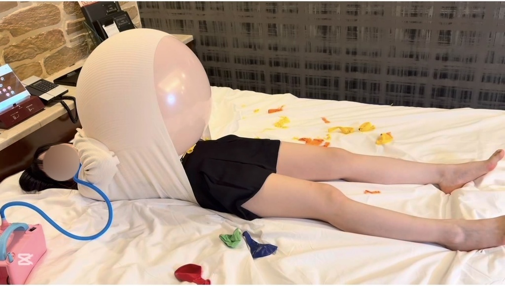ベッドに横になり、白いニットの中でふくらんだ風船に押されるひなた