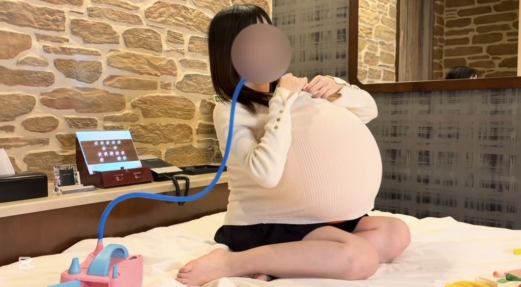 白いニットの中で大きくふくらんだ風船を抱えて座るひなた