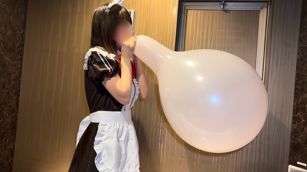 メイド服のひなたが白い16インチ風船を口で膨らませているところ
