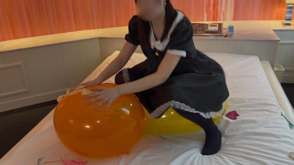 オレンジの風船に座って割ろうとするひなた