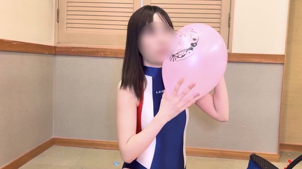 ピンクのキャラクター風船をふくらませるひなた