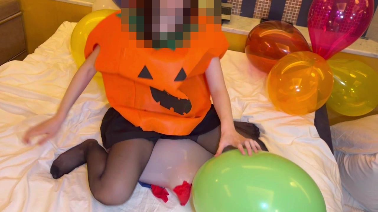 緑の風船を押さえてしゃがむかぼちゃのコスプレのひなた