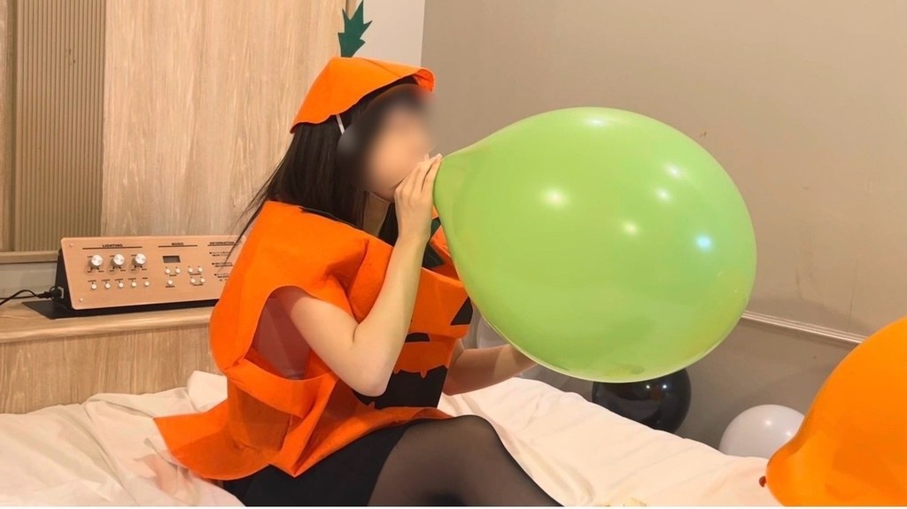 緑の16インチ風船を口でふくらませるひなた