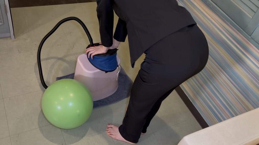 ポンプで膨らませた緑の風船とスーツ姿のひなた