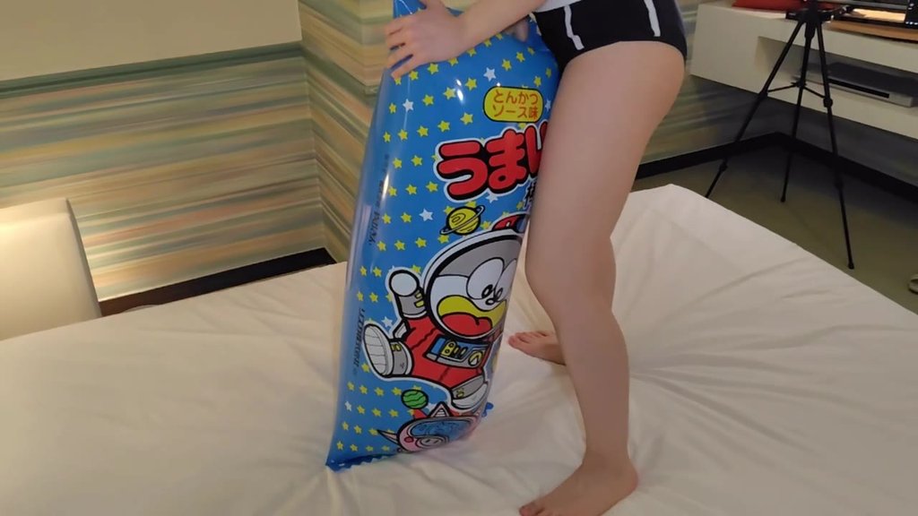 うまい棒柄のビニールクッションを縦に立てて支えるひなた