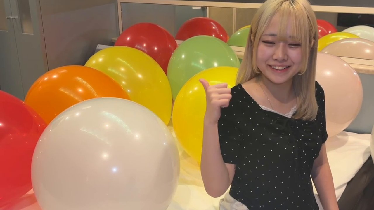 カラフルな風船に囲まれて笑顔でポーズする町田さん