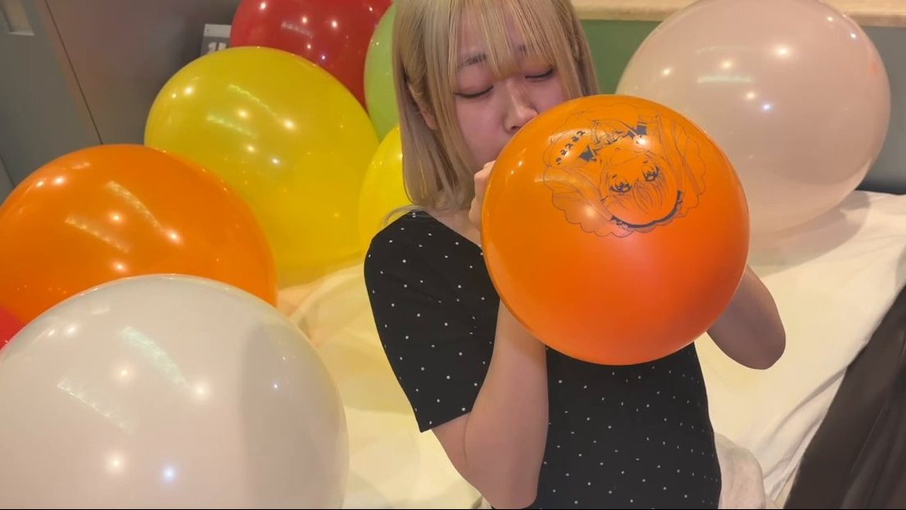 イラスト入りのオレンジの風船を膨らませはじめる町田さん