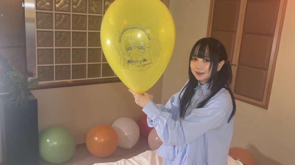膨らませた黄色いイラスト風船を持ってほほえむ望月みうなさん