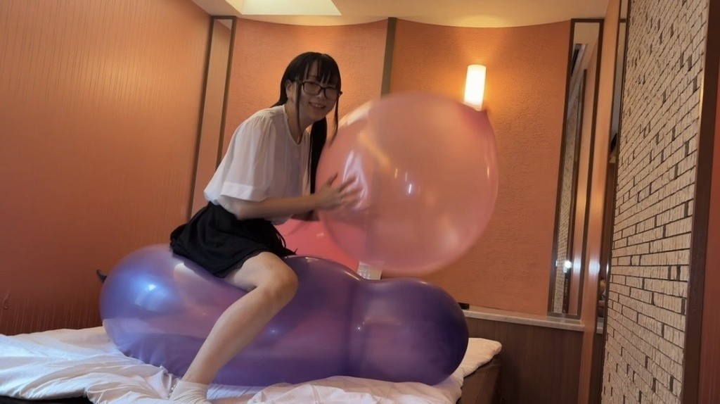 紫の風船に座りながら、ピンクの風船に手をのばす望月みうなさん