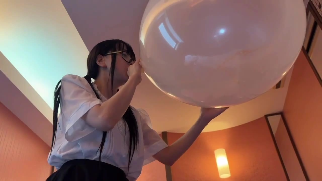 下から見上げたアングルで、頭より大きくなった透明な風船に息を吹き込む望月みうなさん