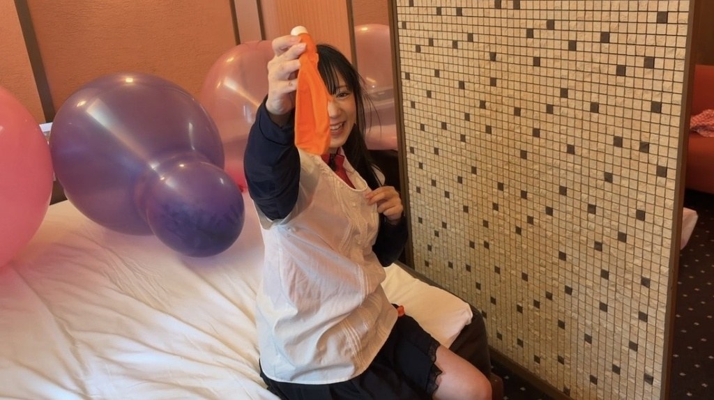 割れたオレンジの風船を手に持って笑顔を見せる望月みうなさん