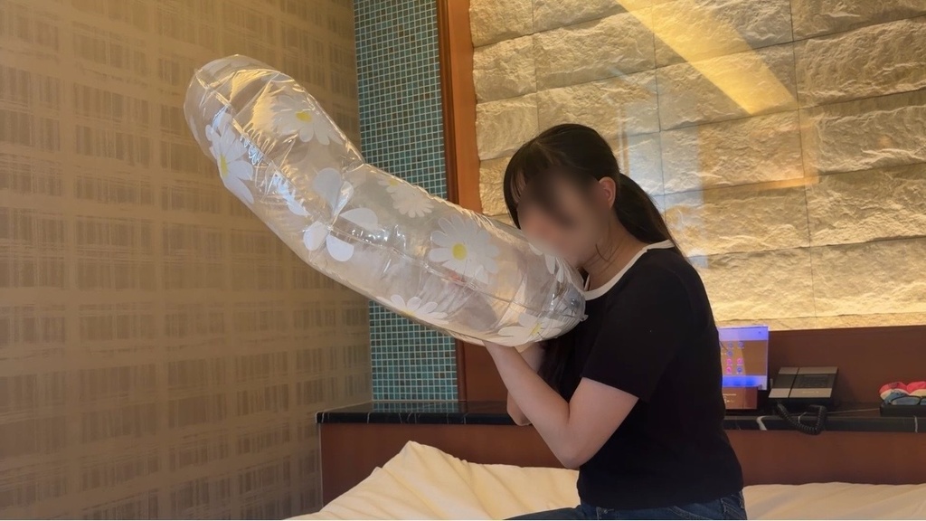 ららさんが花柄の透明な浮き輪を口で膨らませているところ