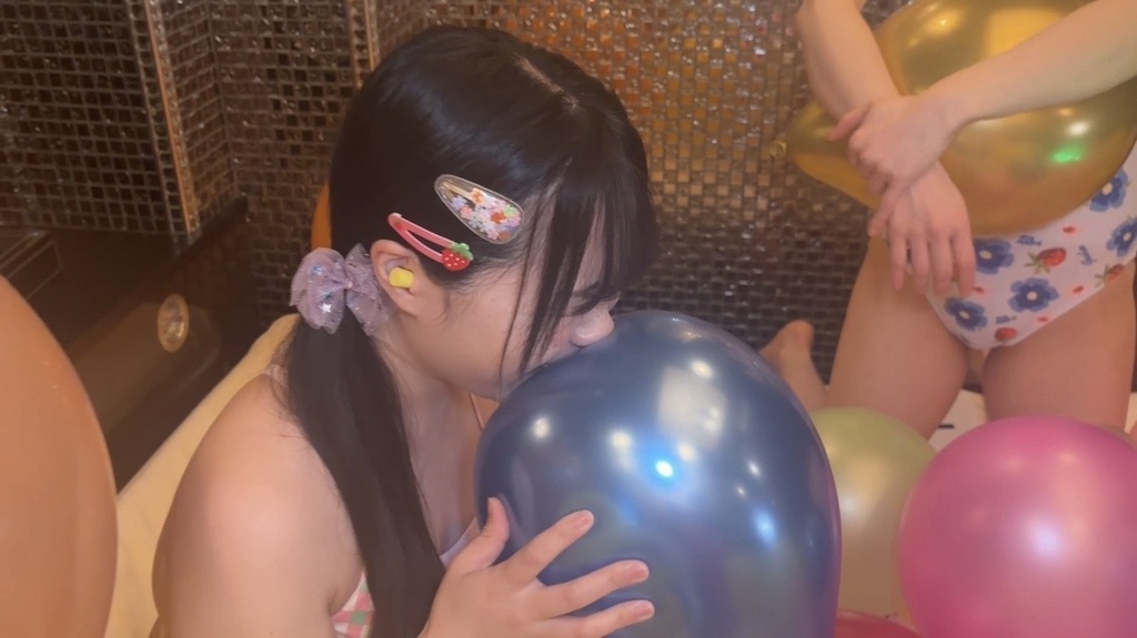 青い風船を抱えて割ろうとする様子