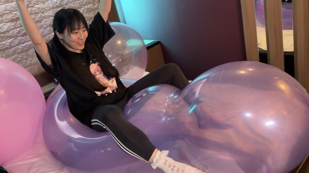 紫の巨大風船に座って両手を上げる夢姫しほさん